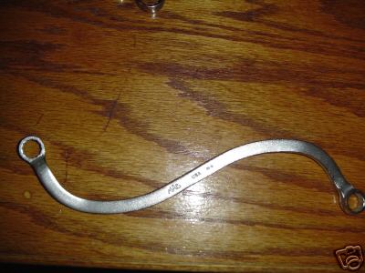 1990 Ford Bronco - A curved wrench with two rings, marked 'MAC' and 'USA', lies on a wooden surface.
