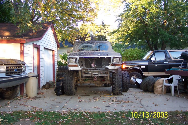 1978 Ford Bronco, front view, disassembled, with large tires, parked next to a black Bronco