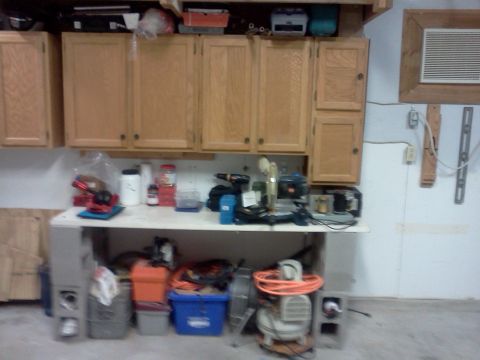 1996 Ford Bronco - A cluttered workbench in a garage, filled with tools and storage containers.