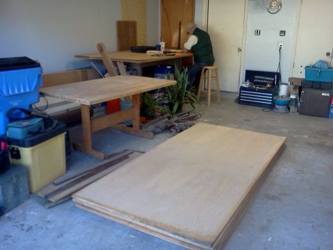 1996 Ford Bronco - A person works at a workbench in a garage filled with lumber and tools.