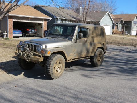 2005 Jeep Wrangler - A silver 2005 Jeep Wrangler is parked on a residential street, showing its off-road capabilities.