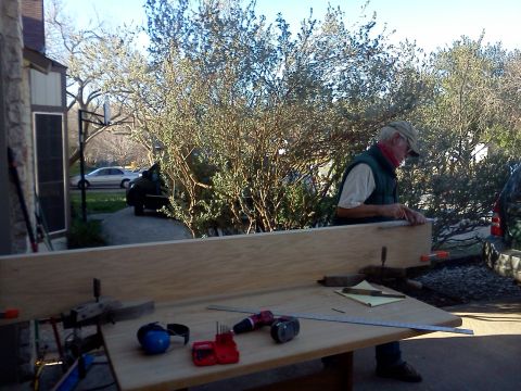 1996 Ford Bronco - Man measures and cuts wood outdoors with tools, with a car parked in the driveway.