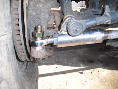 1986 Ford Bronco - Close-up view of the steering linkage and tire assembly on a vehicle.