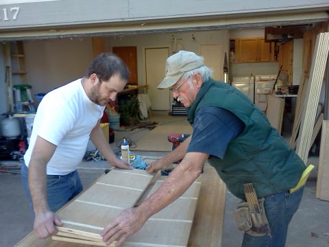 1996 Ford Bronco - Two men are seen working together on wooden panels inside a garage.