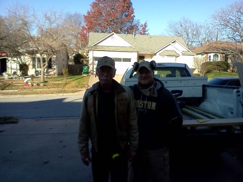 1996 Ford Bronco - Two men stand in front of a pickup truck with lumber in the bed, with houses in the background.