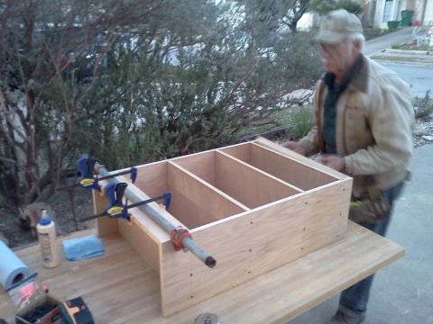 1996 Ford Bronco - A man works on assembling a wooden shelving unit with clamps on a table outside.