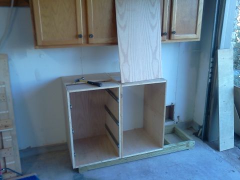 1996 Ford Bronco - Two unfinished cabinet boxes with drawer slides are assembled on a wooden base, with wall cabinets above.