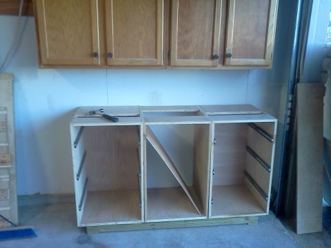 1996 Ford Bronco - A partially constructed cabinet base, drawer slides and a hammer resting on its surface, is shown in a workshop setting with overhead cabin…