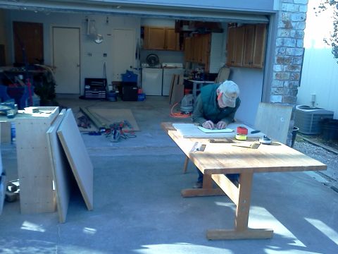 1996 Ford Bronco - A man is focused on his work at a table in a garage, surrounded by tools and building materials.