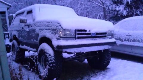 1989 Ford Bronco - A lifted 1989 Ford Bronco is parked outside in the snow, with another vehicle visible to the right.