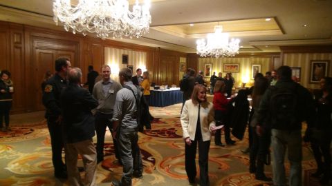 1993 Ford Taurus - A group of people are gathered in a well-lit room, conversing near a table with refreshments.