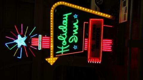 1993 Ford Taurus - A neon sign for Holiday Inn features a starburst and an arrow pointing downwards.