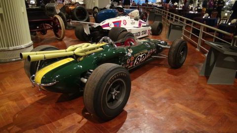 1993 Ford Taurus - Two vintage race cars displayed indoors on a wooden floor.