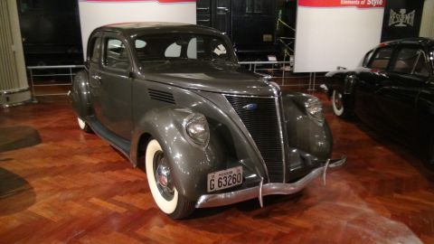 1993 Ford Taurus - A 1937 Ford Coupe is displayed indoors, with another vehicle partially visible to its right.