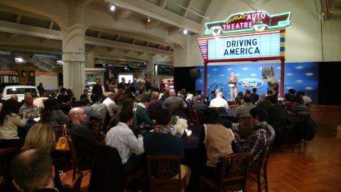 1993 Ford Taurus - A white Ford van is visible in the background at an indoor event with a stage and audience.