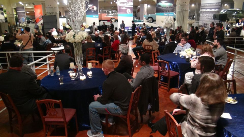 Museum event with guests seated at blue-clothed tables