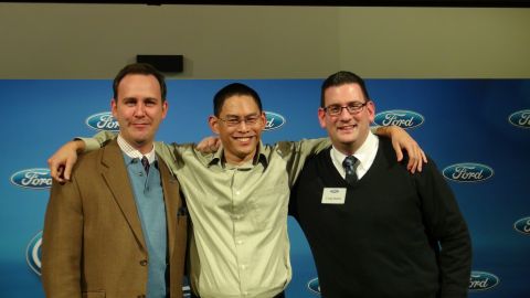 1993 Ford Taurus - Three men pose for a photo in front of a backdrop the Ford logo.