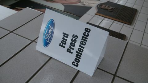 1993 Ford Taurus - A sign indicates a Ford press conference is taking place, with the Ford logo visible.