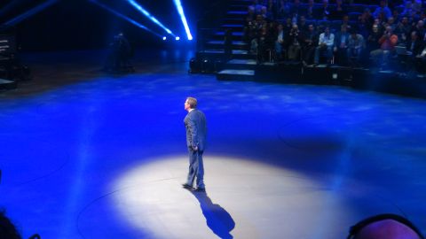 1993 Ford Taurus - A man stands alone on a stage illuminated by blue spotlights, facing away from the audience.