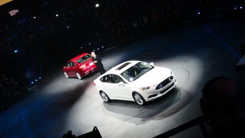 1993 Ford Taurus - Two Ford sedans are presented on a stage, one white and one red, with a presenter nearby.