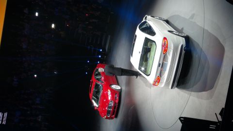 1993 Ford Taurus - Two cars are displayed on a stage with a presenter next to one of them.