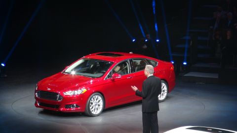1993 Ford Taurus - A red sedan is presented on a stage with a presenter gesturing towards it.