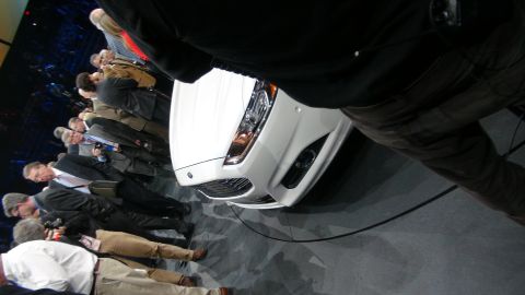 1993 Ford Taurus - A white sedan is presented to a crowd of onlookers at an auto show.