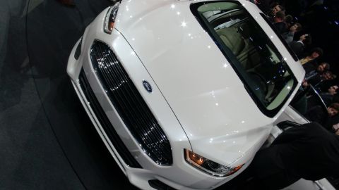 1993 Ford Taurus - A white Ford sedan is displayed at an auto show, with its distinctive grille and headlights visible.