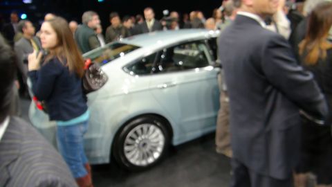 1993 Ford Taurus - A light blue sedan is displayed at an auto show with onlookers.