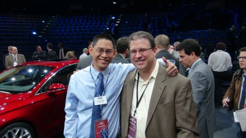 1993 Ford Taurus - A red car is visible next to a man wearing a blue shirt and tie at an event.