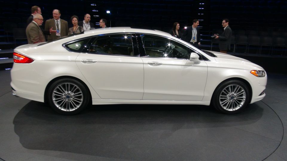 White sedan on display with people in the background