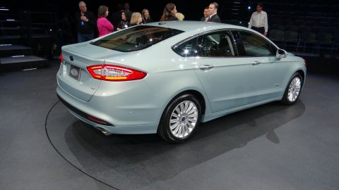 1993 Ford Taurus - A light blue sedan is displayed on a rotating platform with an audience in the background.