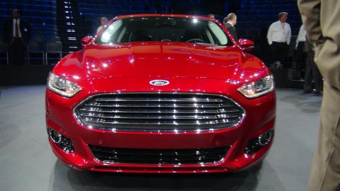 1993 Ford Taurus - A bright red Ford sedan is displayed with its front end prominently visible, a large chrome grille.