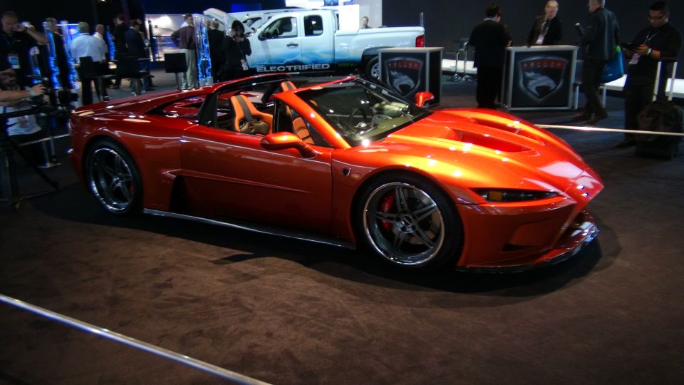 Orange convertible sports car with tan interior on display