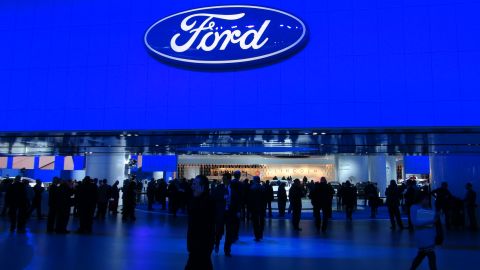1993 Ford Taurus - People gather at an auto show in front of a large Ford logo displayed on a blue screen.