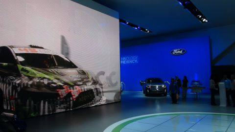 1993 Ford Taurus - A Ford Fiesta race car is displayed on a large screen next to a Ford Explorer at an auto show.