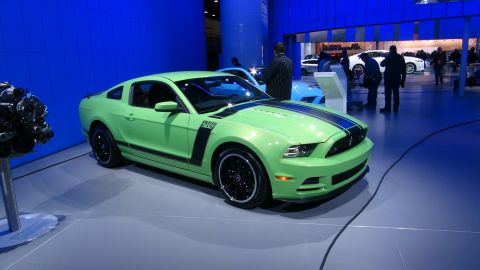 1993 Ford Taurus - A green Ford Mustang Boss 302 is displayed at an auto show with other vehicles in the background.