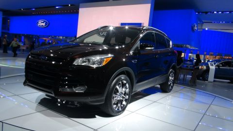 1993 Ford Taurus - A dark brown Ford Escape is displayed on a white platform at an auto show with a blue Ford logo in the background.