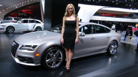 1993 Ford Taurus - A silver sedan is displayed at an auto show with a woman posing next to it. The Audi logo is visible in the background.
