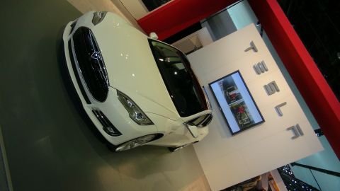 1993 Ford Taurus - A white Tesla Model S is displayed at an auto show with the brand's logo visible.