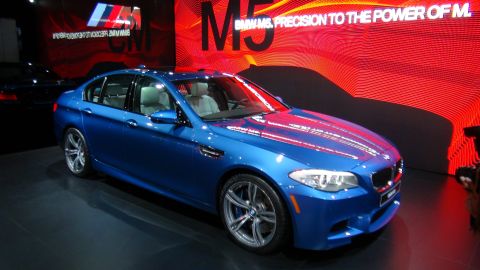 1993 Ford Taurus - A blue BMW M5 sedan is displayed at an auto show with "BMW M5 PRECISION TO THE POWER OF M" text in the background.