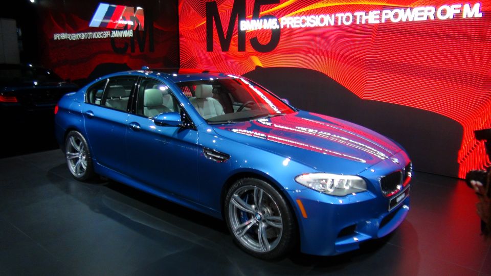 Blue BMW M5 sedan with M badge on grille, 3/4 front view