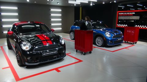 1993 Ford Taurus - Two Mini Cooper John Cooper Works cars are displayed in a showroom with red tool carts.