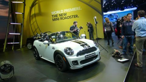 1993 Ford Taurus - A white Mini Cooper convertible is displayed with a backdrop announcing "World Premiere. The New Mini Roadster."