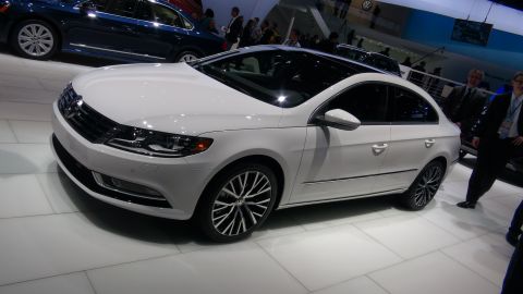 1993 Ford Taurus - A white Volkswagen sedan is shown at an auto show with another vehicle in the background.