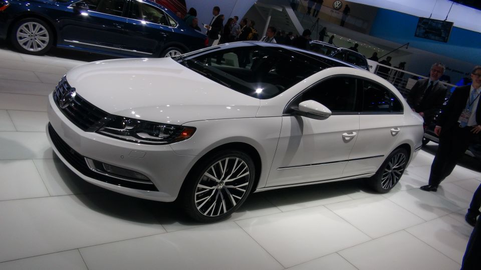 White Volkswagen sedan on display, with a blue car behind it