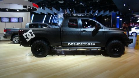 1993 Ford Taurus - Black Toyota Tundra pickup truck with DC Shoes branding and roof rack is displayed at an auto show.