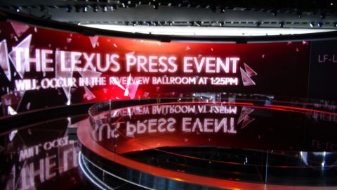 1993 Ford Taurus - A digital display announces a Lexus press event, with reflections visible on a curved surface below.
