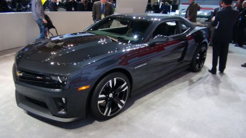 1993 Ford Taurus - A dark gray Chevrolet Camaro ZL1 is displayed at an auto show, with people in the background.