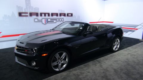 1993 Ford Taurus - Black convertible Camaro with red stripes on hood and "CAMARO 45TH" text in background.